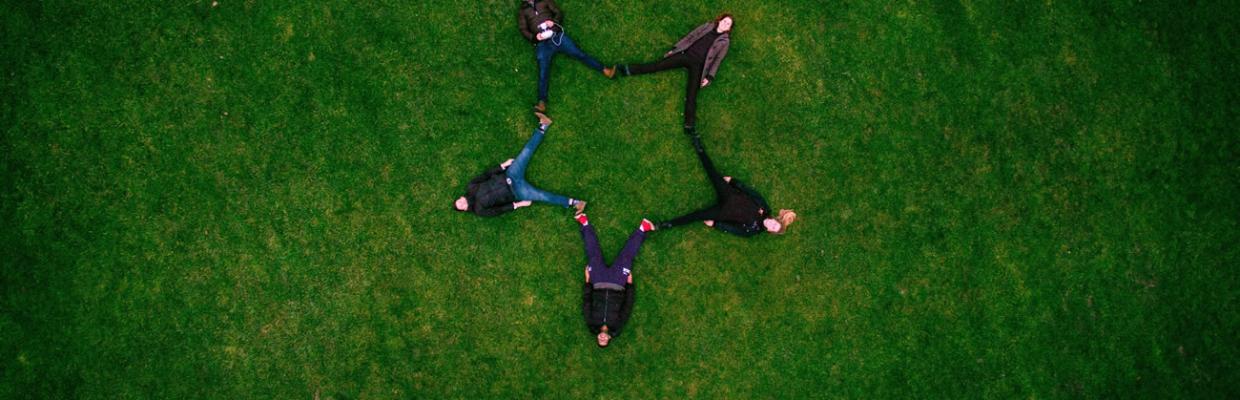 Ragazzi sdraiati in un prato che fanno una stella